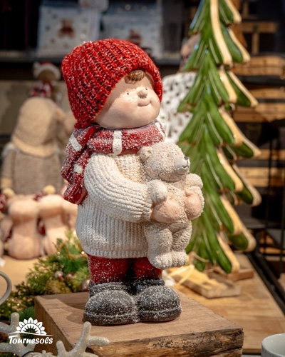 Figurine enfant avec bonnet rouge et ours en peluche, décor de Noël.